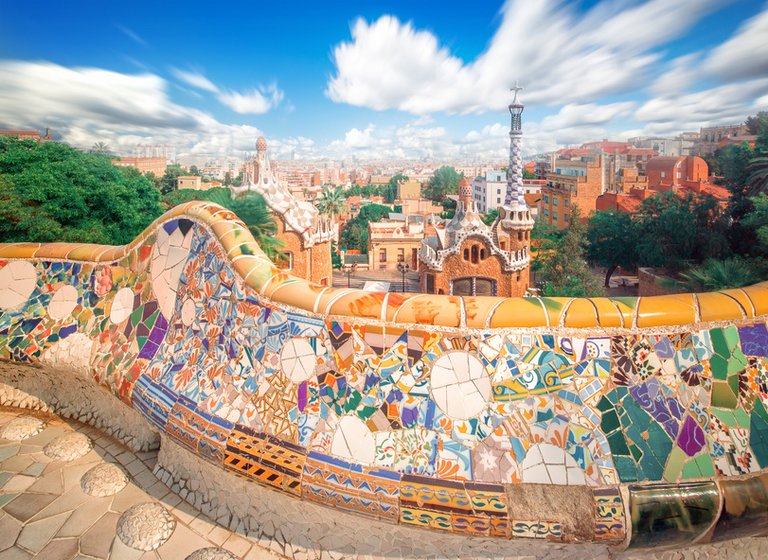 Colorful tiles in Parc Güell in Barcelona with a view on the surrounding buildings