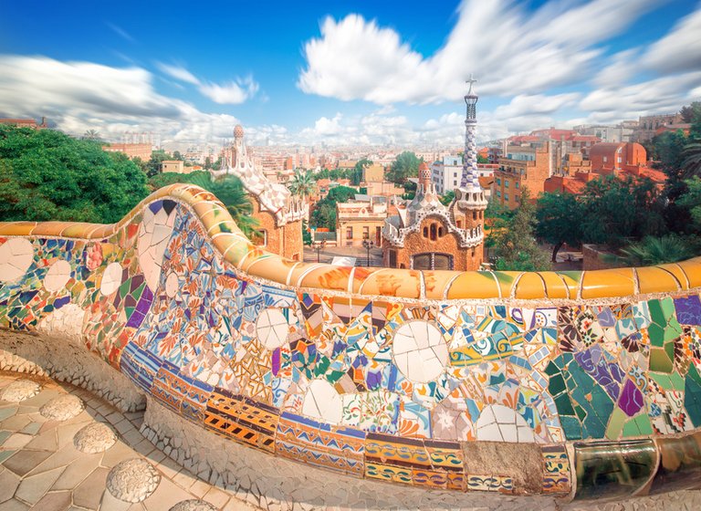 Bunte Fließen in Parc Güell in Barcelona mit Blick auf die umlegenden Gebäude