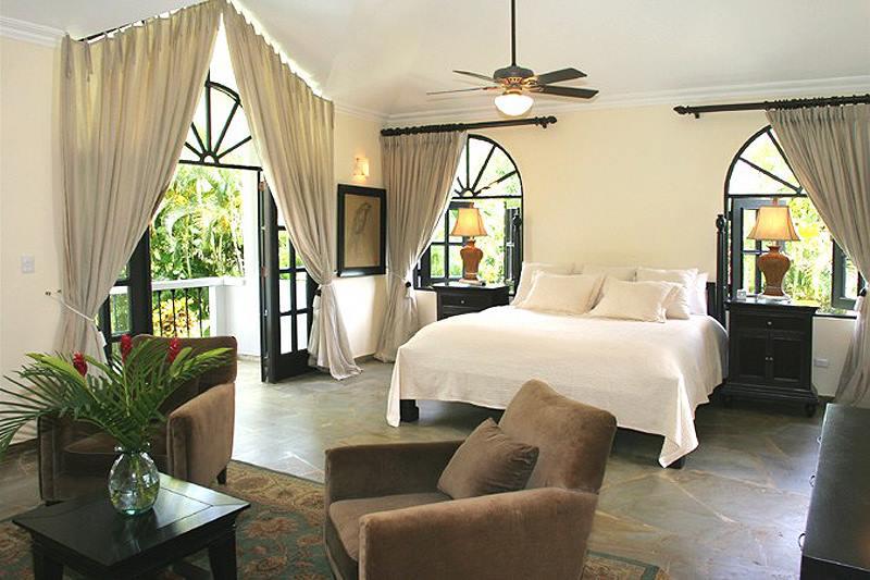 Zimmer mit Doppelbett und Sitzecke mit großen Fenstern und in Natur Tönen gehalten